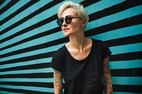Tattooed woman in black tee with stripes background
