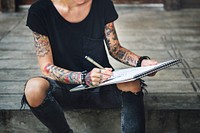 Tattooed woman sketching in a notebook