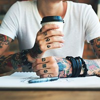 A woman with a lot of tattoos drinking coffee