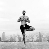 Man practicing yoga on the rooftop and cityscape background<br />