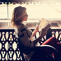 Caucasian woman reading the book at the balcony