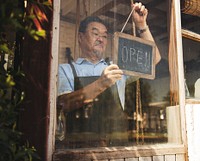 Man hanging an open sign in a flower shop