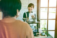 Young woman barista talking with customer