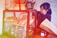 Young patissier woman putting bread pastry on the shelf