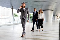 Businessman talking on a phone and business people walking behind him