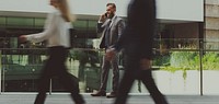 German business man talking on a phone and people walking past him