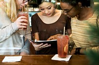 Diverse women looking at a digital tablet in a coffee cafe together