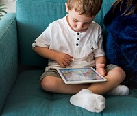 Little boy using a tablet on a couch