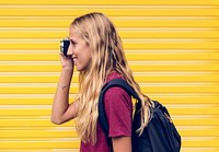 Woman taking a photo yellow wall background