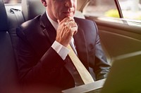 Businessman using laptop on backseat of the car