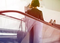 Businesswoman traveling with luggage on escalator