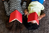 Two playful african children with books covered on their faces