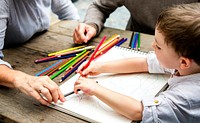 Adults helping young boy with coloring  book