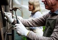 Old caucasian couple fixing wooden door