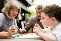 Grandparents helping young boy with coloring  book