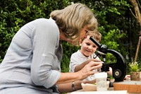 Young boy learning with old woman and telescope