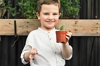 Cheerful young boy holding a cactus plant