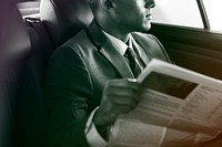 Businessman reading newspaper on the car