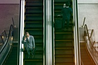 Business people using escalator and talking phone