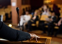 Hand of a Business Woman at a Podium with a Micrphpne 