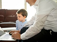 Father working on laptop next to son