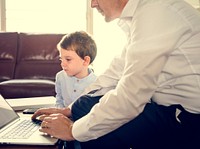 Father teaching little boy how to use laptop