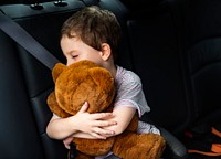 Boy hugging teddy bear in the car