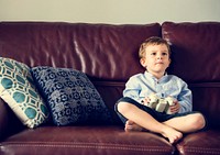Little boy sitting and playing video games on the couch