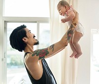 Asian dad holding his baby up with love