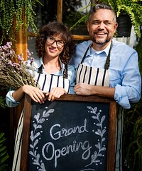 Adult Man and Woman Standing with Grand Opening Sign