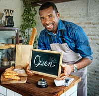 African Man Holding Open Sign in Bakery Shop
