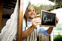 Man Hanging Open Sign by the Glass Window