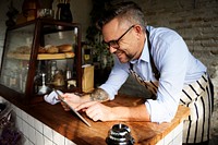 Tattooed man using digital tablet in baker's shop