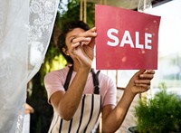 Woman hanging sale board on glass window