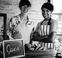 Two Women Stand Together with Open Sign on the Counter