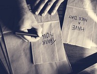 Hands Writing Thankful Words on Paper Bags
