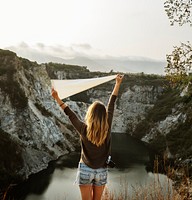 Woman arms raised and holding flag on mountain