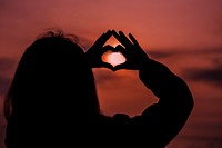 Silhouette of a woman making a heart shape 