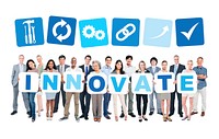 Multi-ethnic group of business and casual people holding cardboards forming innovate and related symbols above.