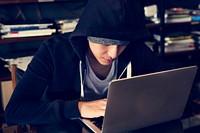 hacker in hoodie using laptop for cyber crime