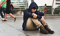 Distressed guy in a hoodie sitting outdoors