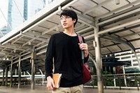 Asian man holding notebook and walking in the city