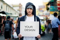 Young asian man holding empty placard outdoors