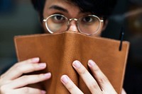 Young asian man using leather book to cover his face