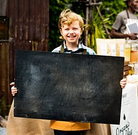 Little boy holding blank banner organic fresh agricultural lemonade stand at farmer market