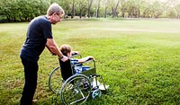 Little Boy On Wheelchair with Grandfather at Outdoors Park