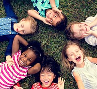 Group of kindergarten kids lying on the grass at park and relax