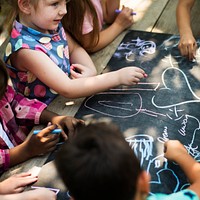 Diverse group of kids drawing on a blackboard