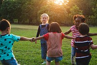 Group of kindergarten kids friends holding hands playing at park