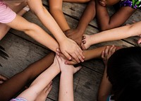 Diverse hands are join together on the wooden table
